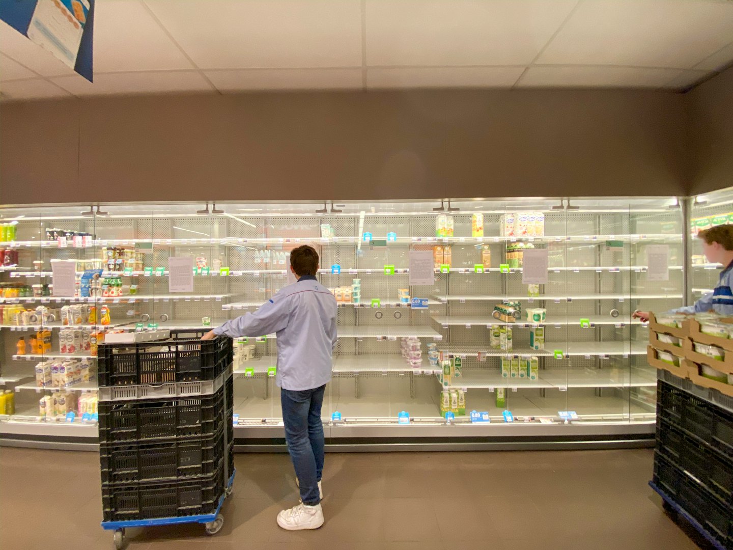 Veikala darbinieks papildina ledusskapja vitrīnas ar kastēm.